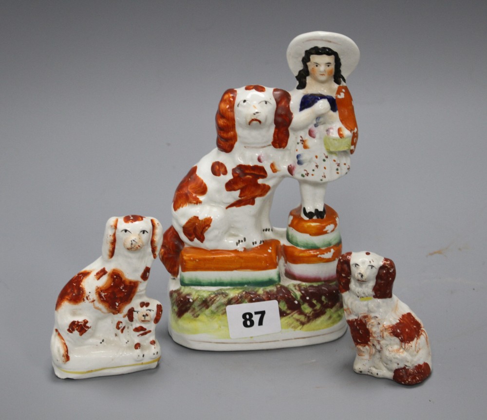 A Victorian Staffordshire girl and spaniel group, height 19cm and two smaller Staffordshire dogs, 9.5cm and 7cm